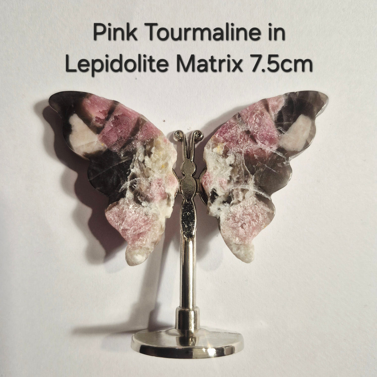 Butterfly-shaped pink tourmaline on a silver stand, with text at the top reading 'Pink Tourmaline in Lepidolite Matrix 7.5cm'.