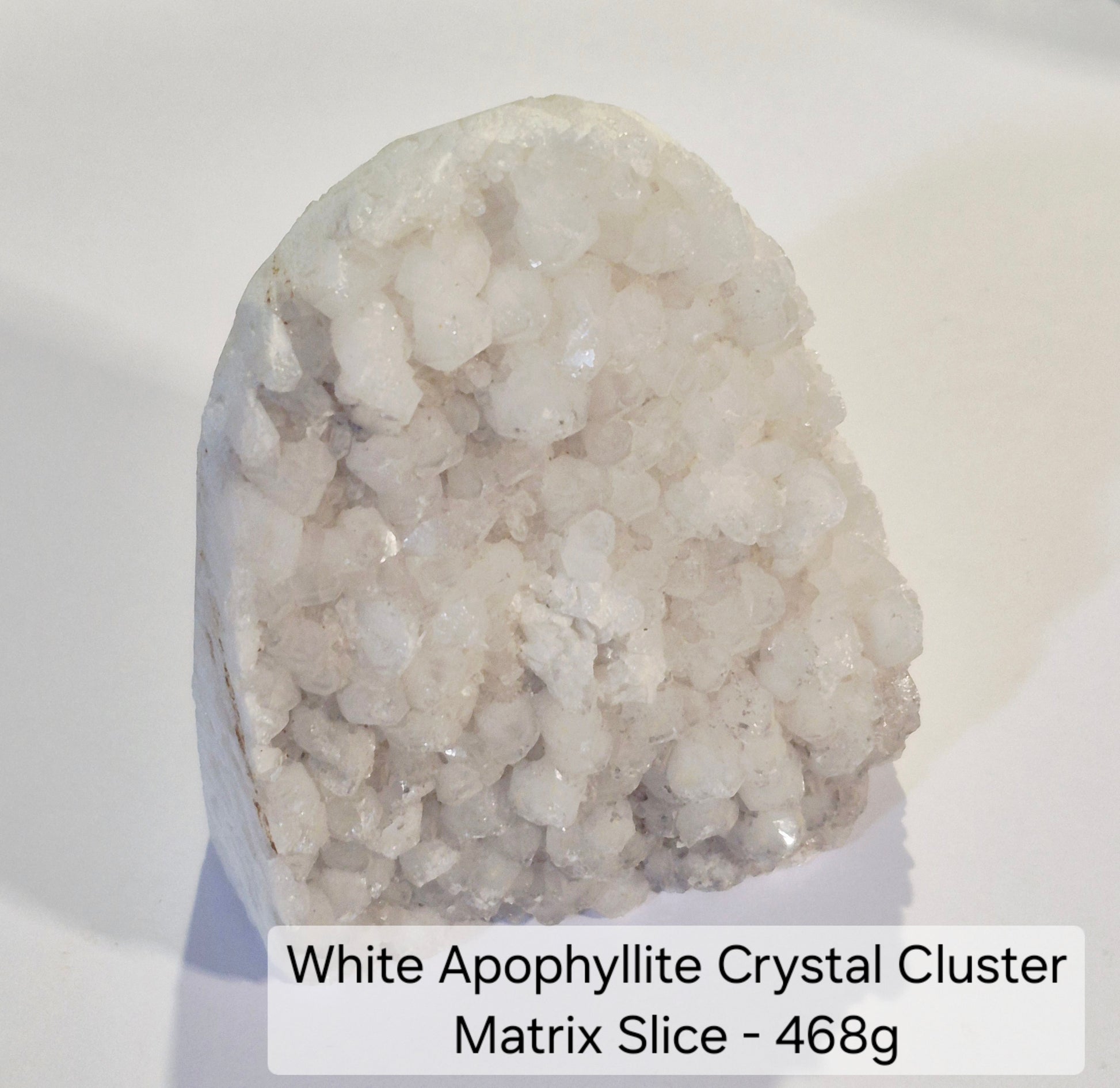 A white apophyllite crystal cluster stone with a textured, bubbly crystalline surface, photographed on a plain white background with a text label at the bottom.