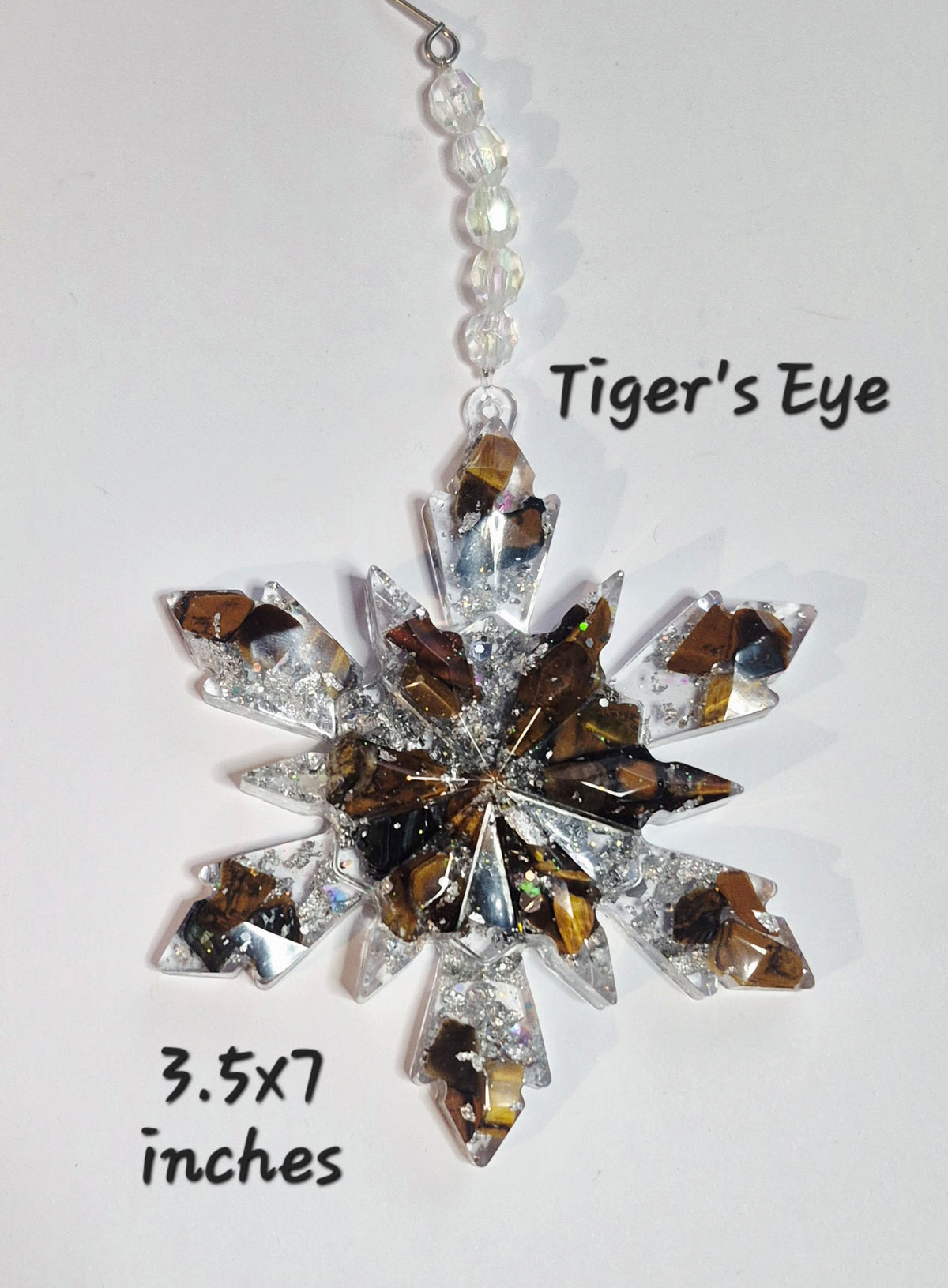 A snowflake-shaped crystal ornament labeled 'Tiger's Eye' with  text indicating '3.5x7 inches'.