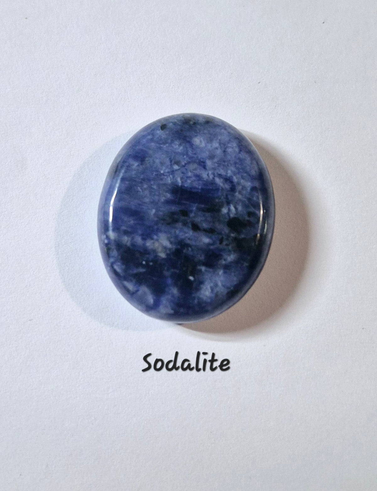 A polished oval worry stone of blue Sunsetsodalite stone with natural white and dark blue marbling, displayed on a white background with the text 'Sodalite' underneath.
