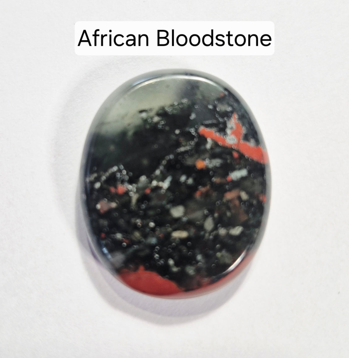 A polished oval African Bloodstone worry stone with a marbled black, gray, and red pattern, shown on a plain white background with a text label at the top reading 'African Bloodstone'.