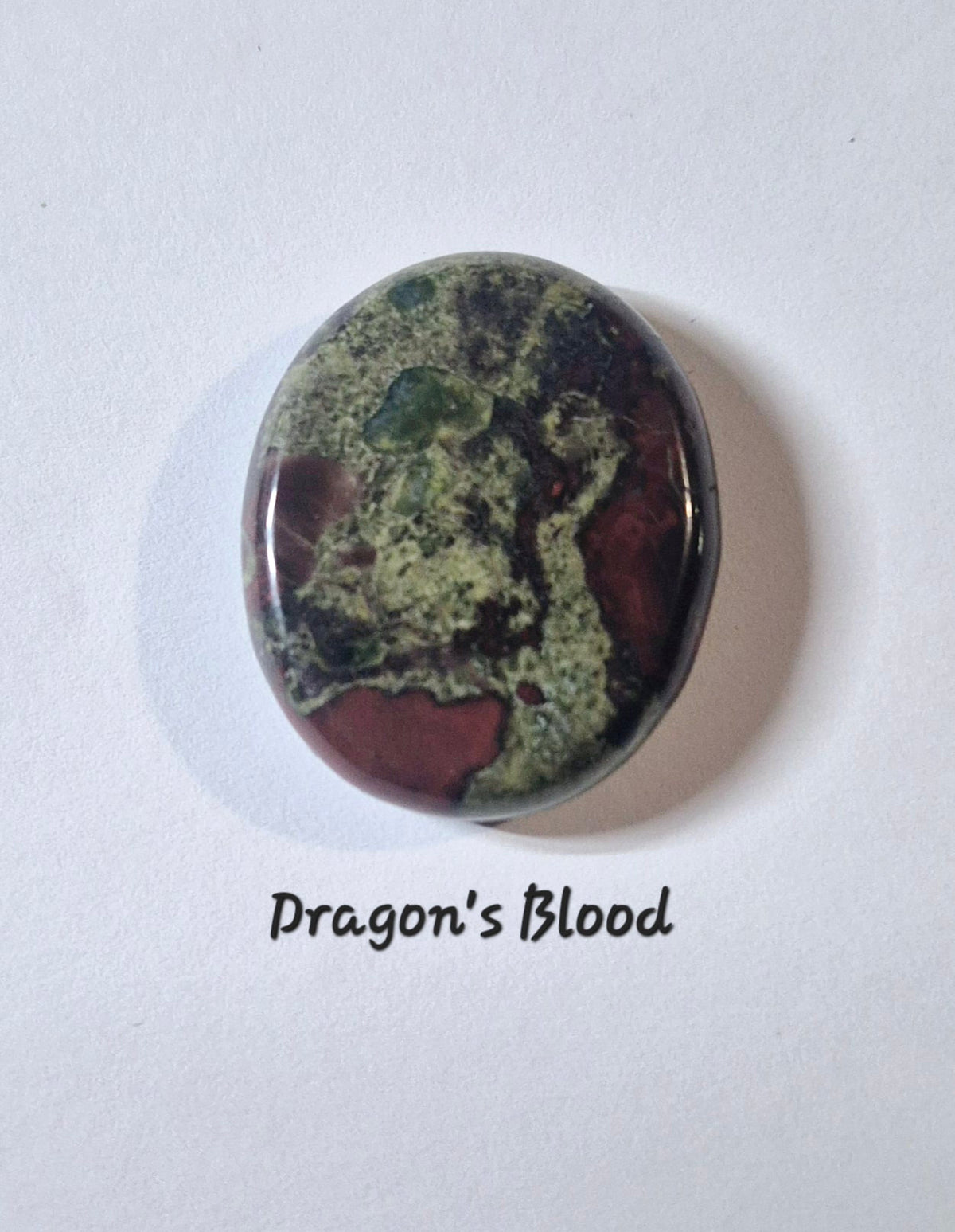An oval worry stone gemstone with a marbled pattern of olive green, dark brown, and reddish-brown, labeled 'Dragon's Blood' on a white background.