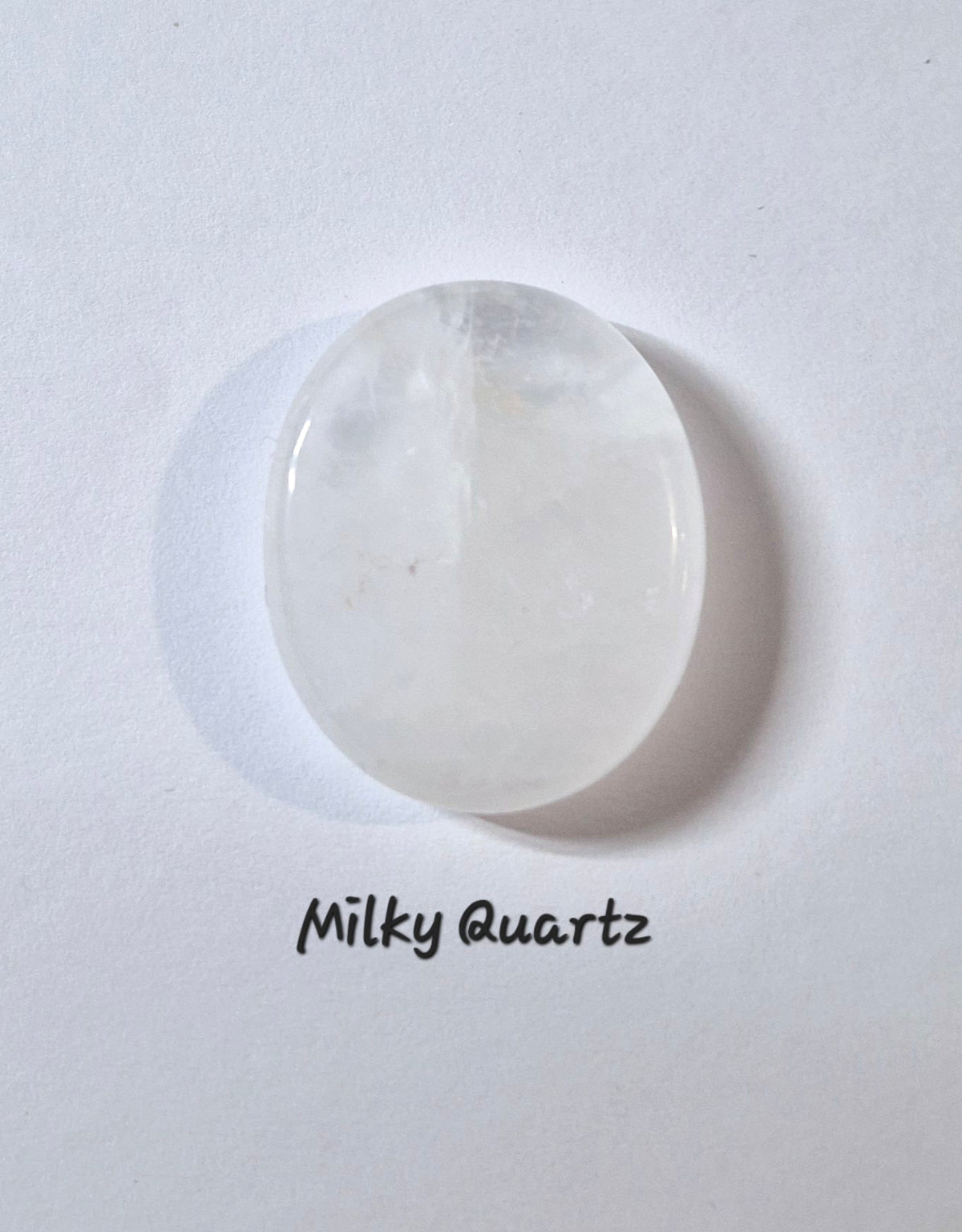 A polished oval worry stone of milky white quartz, labeled 'Milky Quartz' in black text below it, set against a plain white background.