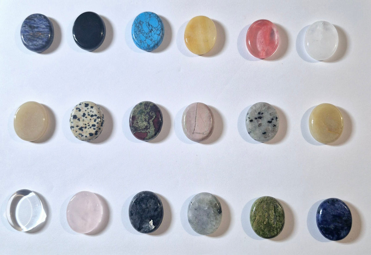 A grid of 15 polished oval gemstone worry stones in various colors and patterns, arranged on a plain white background.