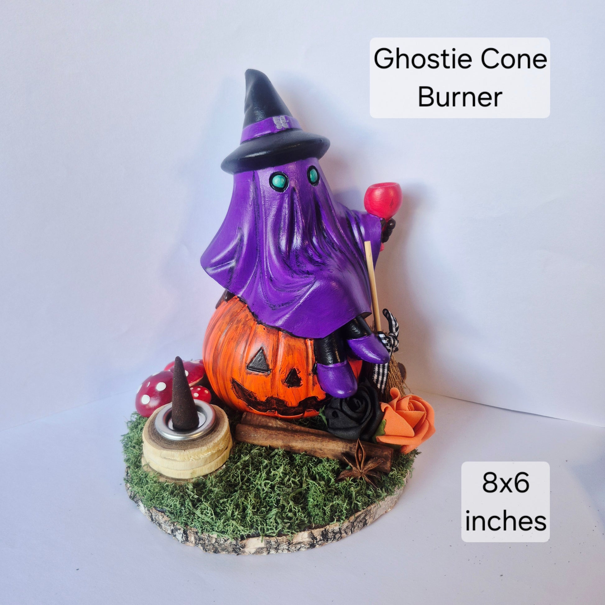 A Halloween-themed ghost cone burner figurine featuring a purple ghost in a witch hat sitting on an orange jack-o'-lantern, with a red cone-shaped flame holder and mossy base. Text overlays indicate 'Ghostie Cone Burner' and '8x6 inches'.