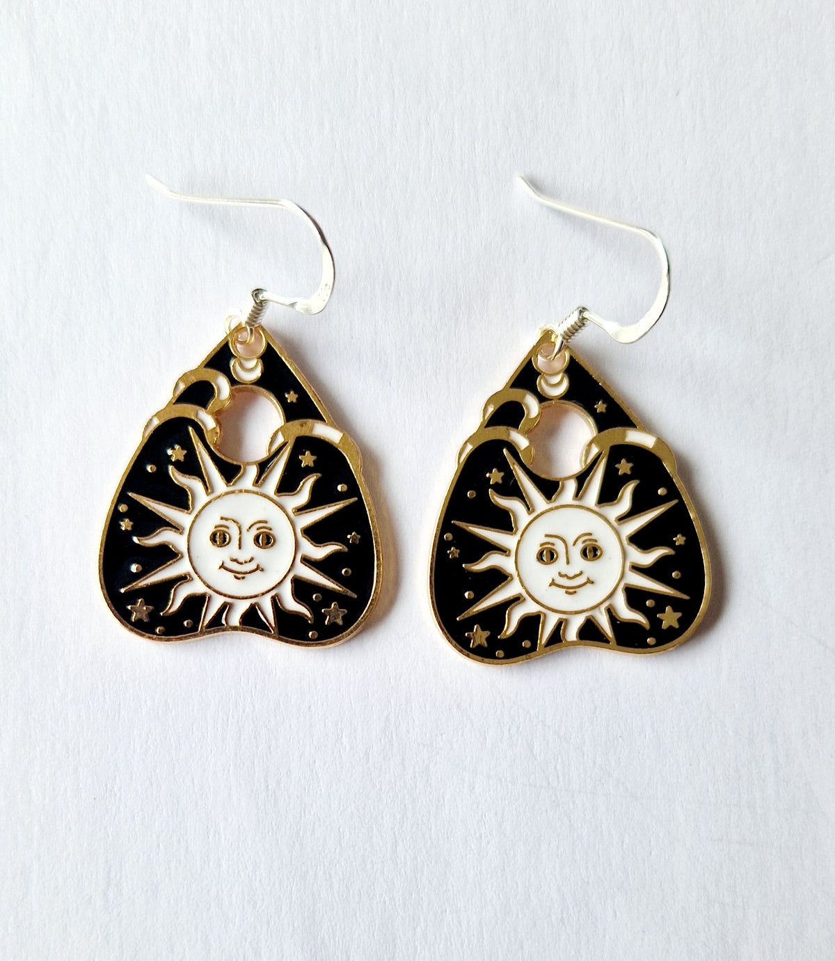 A pair of silver-toned sun planchette dangle earrings on a plain white background.