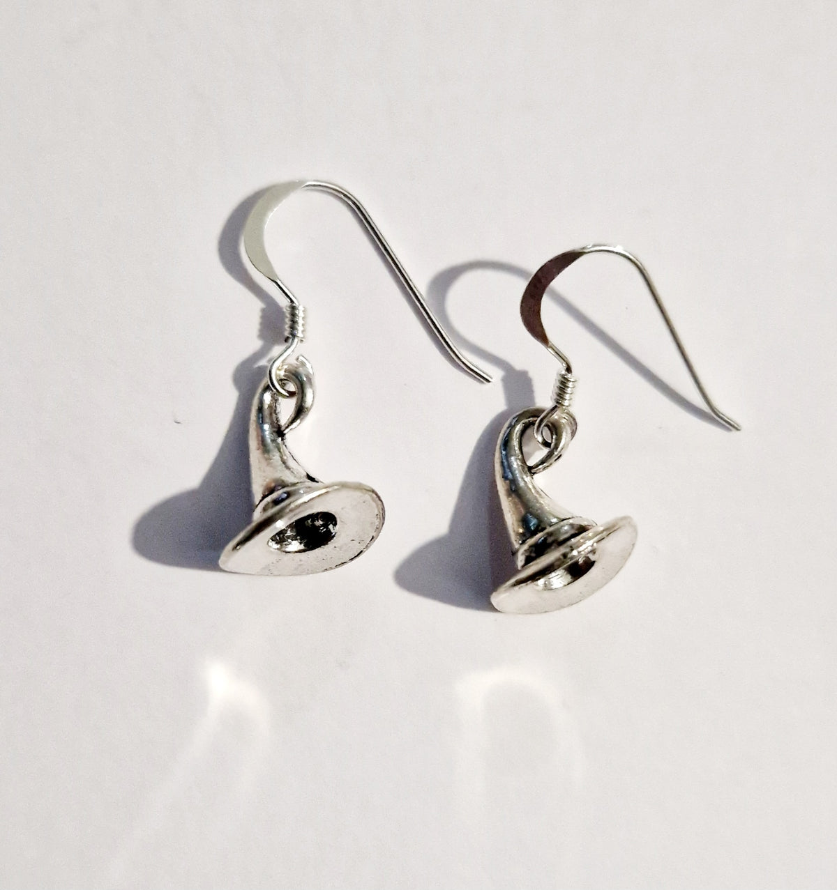 A pair of silver-toned witch hat dangle earrings  shown on a plain white background with soft shadows.