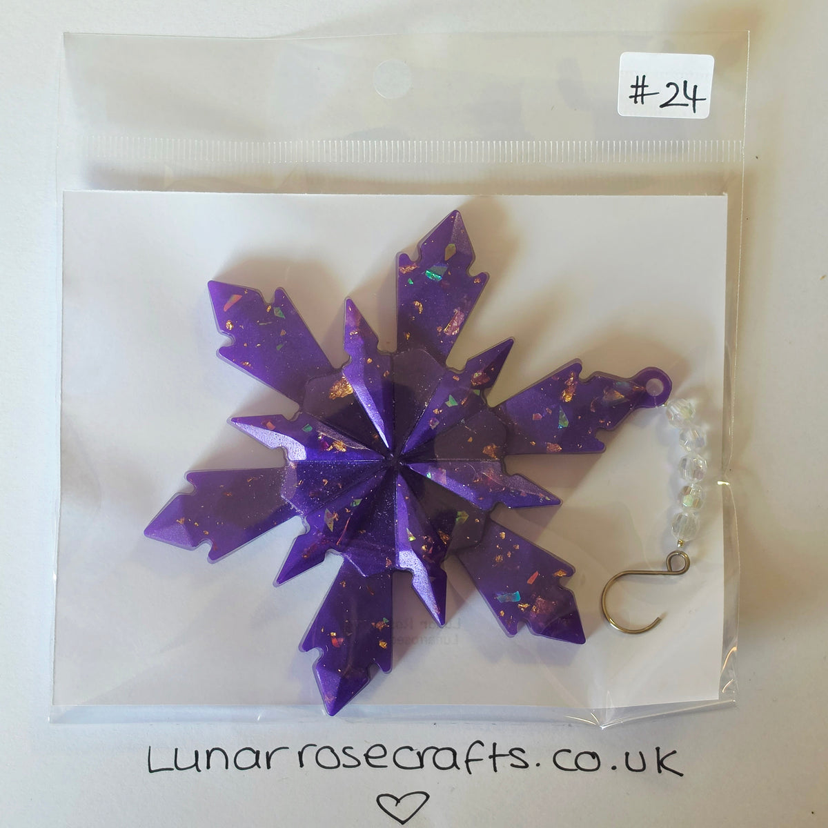 A purple glittery snowflake-shaped craft hook and bead accessory inside a clear plastic bag with a white backing card. A small white label reads '#24' and the card shows the brand name 'Lunarrosecrafts.co.uk'