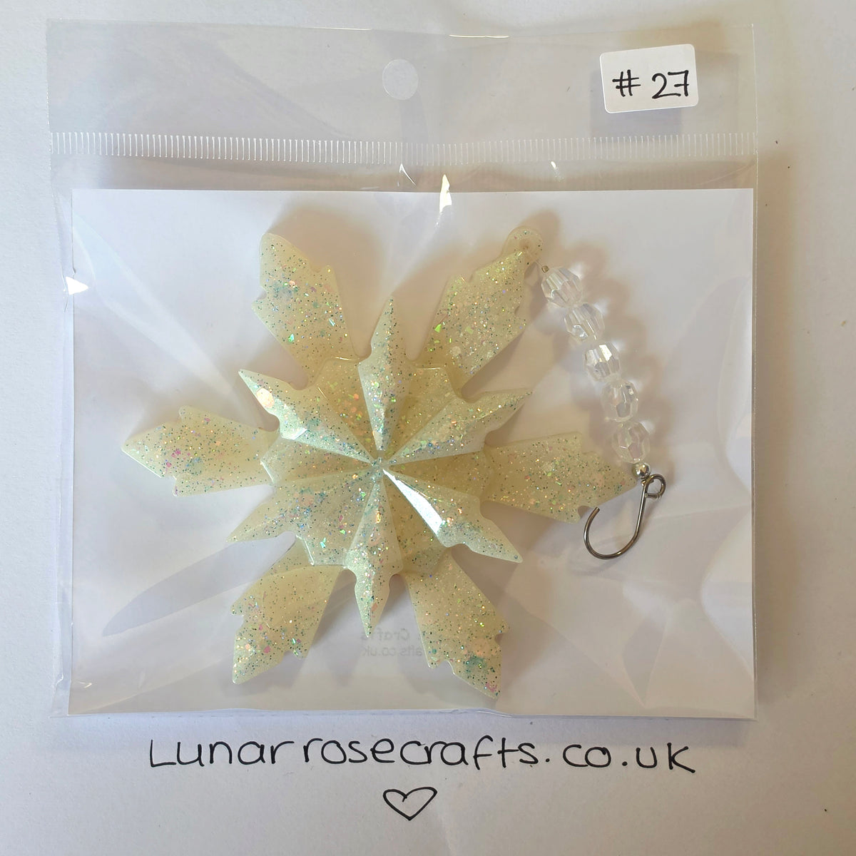 A packaged handmade snowflake hanging  decoration with a pale iridescent glitter body, a clear beaded chain, and a silver lobster clasp, sealed in a clear plastic bag with a handwritten label '#23' and 'Lunarrosecrafts.co.uk'
