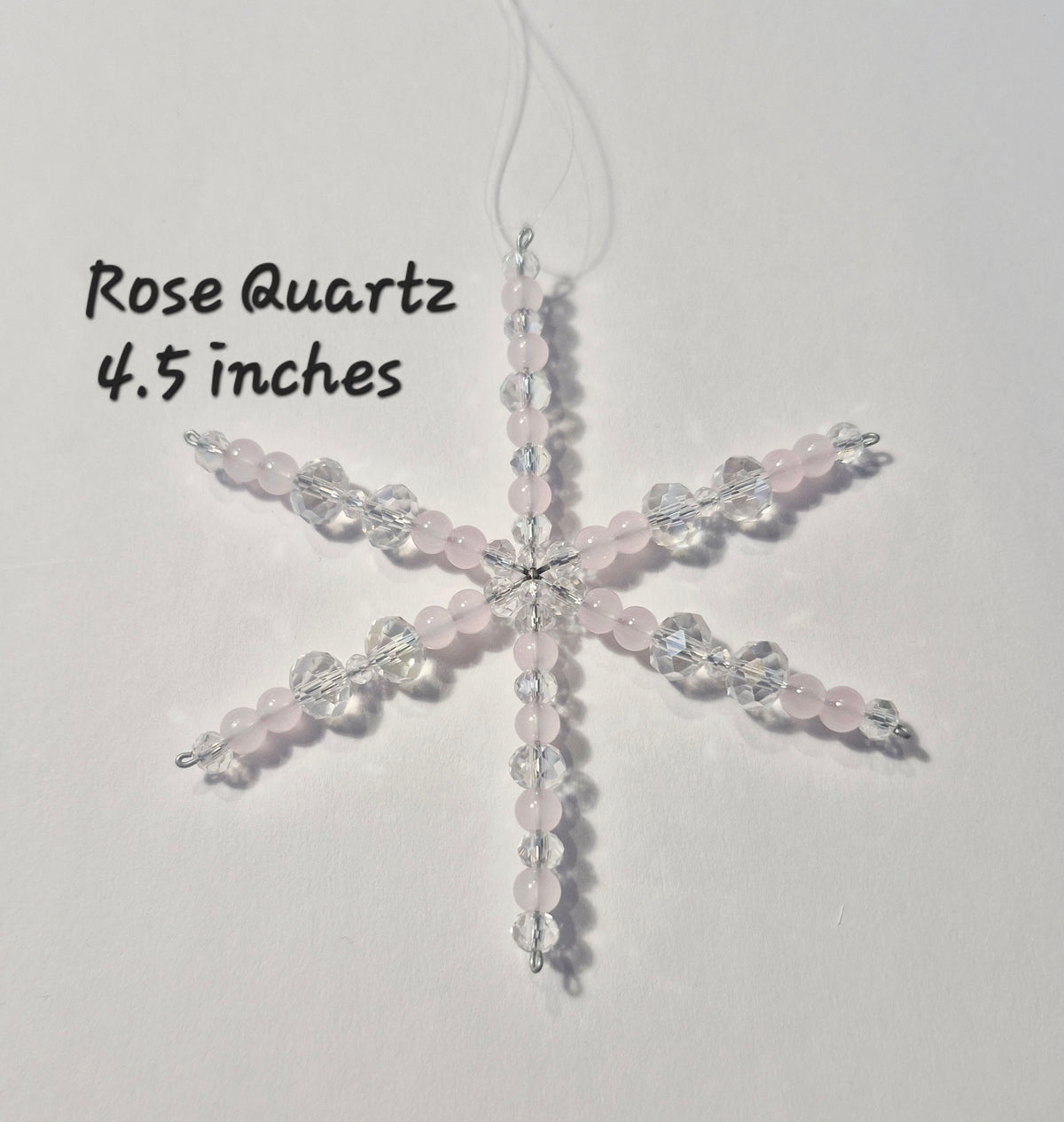A six-pointed star-shaped beaded ornament made of pale pink rose quartz beads and clear faceted crystal beads, hanging against a plain white background with handwritten text reading 'Rose Quartz 4.5 inches'.