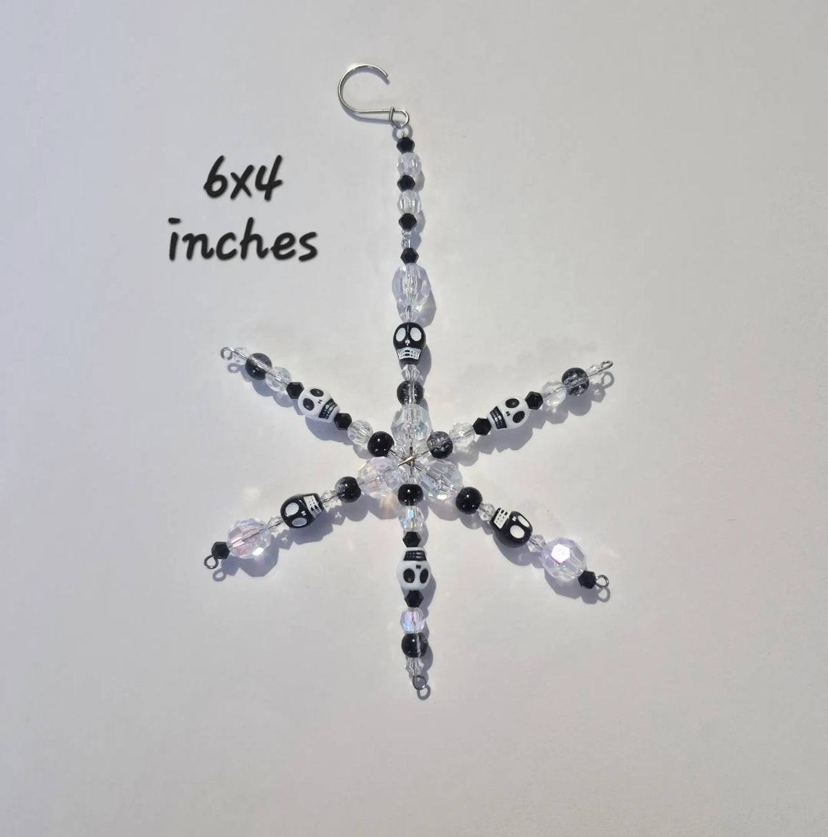 A handmade snowflake-shaped beaded ornament with a silver hook at the top, featuring black, white, and clear beads, shown on a plain light background with '6x4 inches' text overlay.